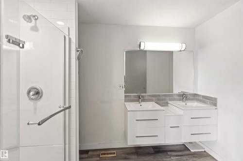 Bathroom featuring two vanities, a stall shower, and dark wood-style floors - 11615 150 Avenue, Edmonton, AB - Indoor Photo Showing Bathroom