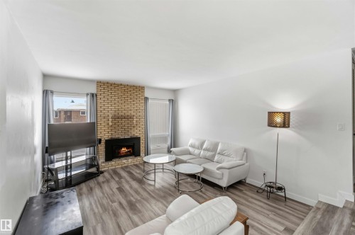 Living area with wood finished floors and a brick fireplace - 11615 150 Avenue, Edmonton, AB - Indoor Photo Showing Living Room With Fireplace