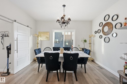 Dining room featuring a barn door, light wood-style flooring, and a chandelier - 7803 Yorke Road, Edmonton, AB - Indoor Photo Showing Dining Room