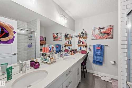 Bathroom with a stall shower, double vanity, a textured ceiling, and dark tile patterned flooring - 7803 Yorke Road, Edmonton, AB - Indoor Photo Showing Bathroom