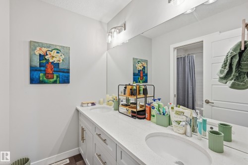 Bathroom featuring double vanity, a shower with shower curtain, and a textured ceiling - 7803 Yorke Road, Edmonton, AB - Indoor Photo Showing Bathroom