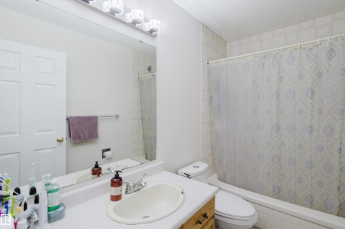 Full bathroom featuring vanity, shower / bath combo with shower curtain, and a textured ceiling - 236 Lago Lindo Crescent, Edmonton, AB 