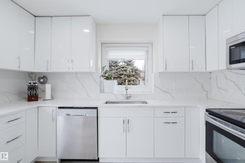 Kitchen with stainless steel appliances, white cabinetry, modern cabinets, and light stone countertops - 236 Lago Lindo Crescent, Edmonton, AB 