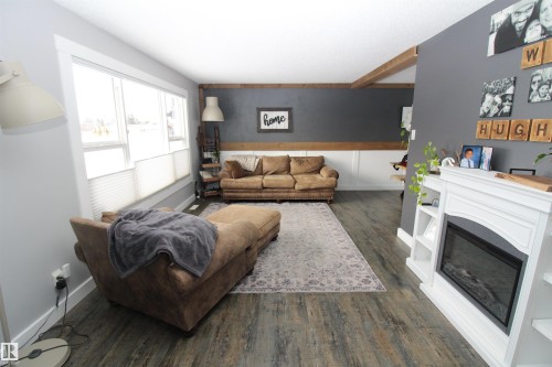 Living room featuring dark wood-style flooring and a glass covered fireplace - 10319 106 Ave, Westlock, AB - Indoor Photo Showing Living Room With Fireplace