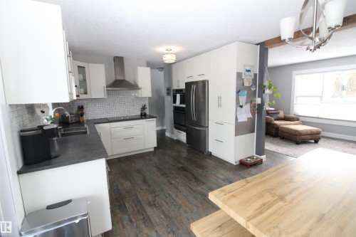Kitchen featuring dark countertops, white cabinets, freestanding refrigerator, tasteful backsplash, and dark wood-type flooring - 10319 106 Ave, Westlock, AB - Indoor Photo Showing Kitchen
