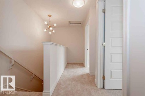 Corridor featuring light carpet, an upstairs landing, and hanging lights - 10 446 Allard Boulevard, Edmonton, AB - Indoor Photo Showing Other Room
