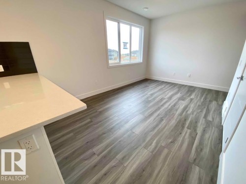 Unfurnished dining area featuring dark wood-type flooring and baseboards - 10 446 Allard Boulevard, Edmonton, AB - Indoor Photo Showing Other Room