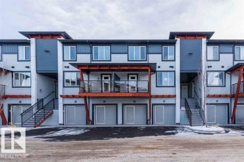 View of building exterior featuring stairs and an attached garage - 10 446 Allard Boulevard, Edmonton, AB - Outdoor With Facade