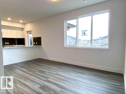 Unfurnished living room featuring baseboards and dark wood finished floors - 10 446 Allard Boulevard, Edmonton, AB - Indoor Photo Showing Kitchen