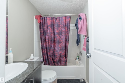 Full bathroom with vanity, shower / bathtub combination with curtain, and a textured ceiling - 206 3207 James Mowatt Trail, Edmonton, AB - Indoor Photo Showing Bathroom