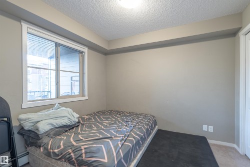 Carpeted bedroom with a textured ceiling and baseboards - 206 3207 James Mowatt Trail, Edmonton, AB - Indoor Photo Showing Bedroom