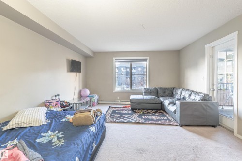 Carpeted living area featuring a baseboard heating unit - 206 3207 James Mowatt Trail, Edmonton, AB - Indoor Photo Showing Living Room