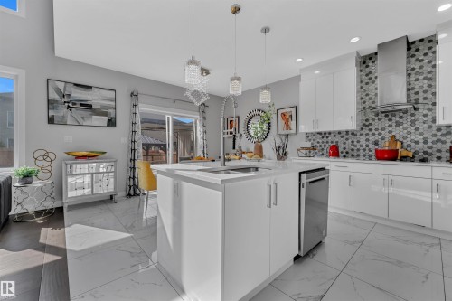 Kitchen featuring white cabinetry, modern cabinets, light marble finish flooring, pendant lighting, and an island with sink - 3607 46 Avenue, Beaumont, AB - Indoor Photo Showing Other Room
