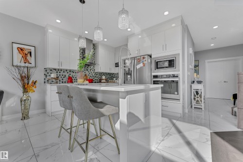 Kitchen featuring a kitchen breakfast bar, a kitchen island, stainless steel appliances, and white cabinetry - 3607 46 Avenue, Beaumont, AB - Indoor