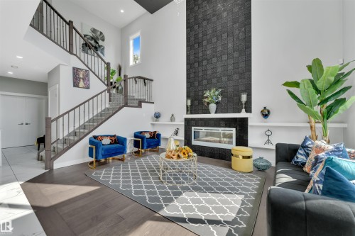Living room with a high ceiling, wood finished floors, a tiled fireplace, and recessed lighting - 3607 46 Avenue, Beaumont, AB - Indoor With Fireplace