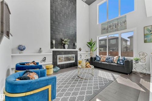 Living area with a high ceiling, wood finished floors, and a tile fireplace - 3607 46 Avenue, Beaumont, AB - Indoor Photo Showing Other Room With Fireplace
