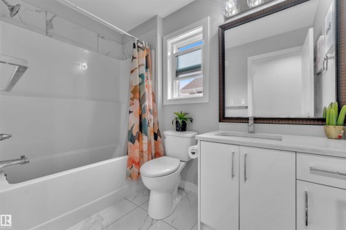 Bathroom featuring vanity, shower / bath combo with shower curtain, and light marble finish floors - 3607 46 Avenue, Beaumont, AB - Indoor Photo Showing Bathroom