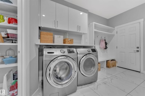 Laundry area with light marble finish flooring, cabinet space, and separate washer and dryer - 3607 46 Avenue, Beaumont, AB - Indoor Photo Showing Laundry Room
