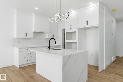 Kitchen featuring white cabinetry, light wood-type flooring, light stone countertops, tasteful backsplash, and a center island with sink - 2408 208 Street, Edmonton, AB - Indoor Photo Showing Kitchen With Upgraded Kitchen