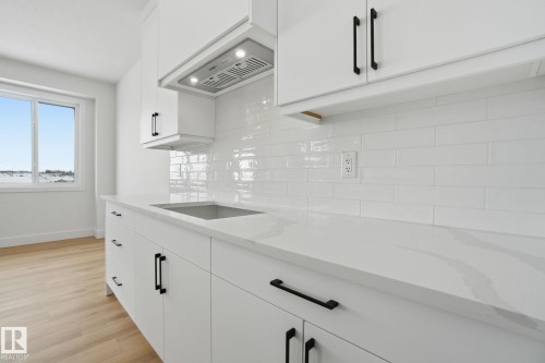 Kitchen featuring white cabinets, light stone counters, light wood-style flooring, and backsplash - 2408 208 Street, Edmonton, AB - Indoor Photo Showing Kitchen With Upgraded Kitchen
