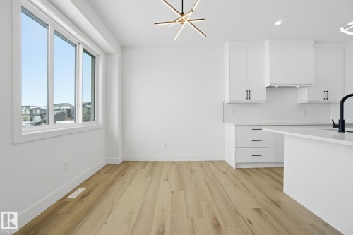 Kitchen featuring hanging lights, white cabinetry, light wood-style flooring, and decorative backsplash - 2408 208 Street, Edmonton, AB - Indoor