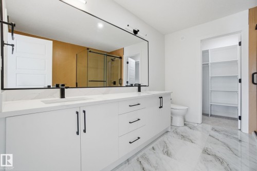 Bathroom featuring double vanity, a stall shower, a spacious closet, and light marble finish flooring - 2408 208 Street, Edmonton, AB - Indoor Photo Showing Bathroom