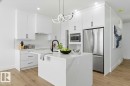 Kitchen with stainless steel appliances, an island with sink, light wood finished floors, tasteful backsplash, and white cabinetry - 2408 208 Street, Edmonton, AB  - Indoor Photo Showing Kitchen With Upgraded Kitchen 