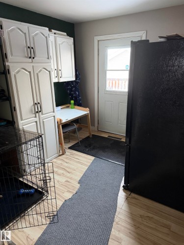 Kitchen with freestanding refrigerator, white cabinetry, light wood-style floors, and light countertops - 4506 53 Avenue, Barrhead, AB - Indoor Photo Showing Other Room