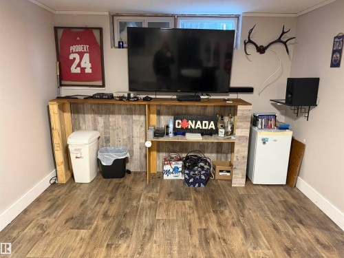 Detailed view of crown molding, wood finished floors, and white refrigerator - 4506 53 Avenue, Barrhead, AB - Indoor Photo Showing Other Room