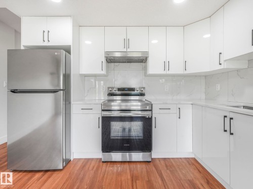 Kitchen with stainless steel appliances, backsplash, white cabinetry, and light stone counters - 120 38 Street, Edmonton, AB - Indoor Photo Showing Kitchen