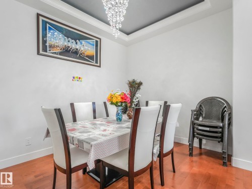 Dining space with wood finished floors, hanging lights, and a tray ceiling - 120 38 Street, Edmonton, AB - Indoor Photo Showing Dining Room
