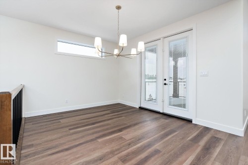 Unfurnished dining area featuring suspended lighting and dark wood-style flooring - 128 Lilac Close, Leduc, AB 