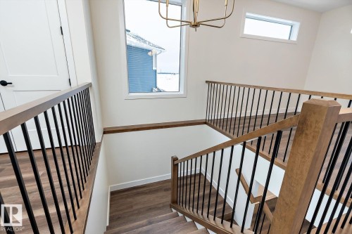 Stairway featuring wood finished floors and hanging lights - 128 Lilac Close, Leduc, AB 