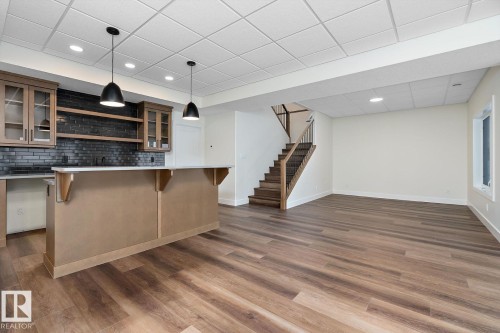 Bar with glass insert cabinets, open shelves, pendant lighting, a paneled ceiling, and backsplash - 128 Lilac Close, Leduc, AB 
