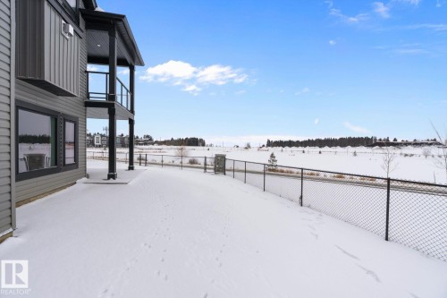 Yard layered in snow with a fenced backyard and a balcony - 128 Lilac Close, Leduc, AB 