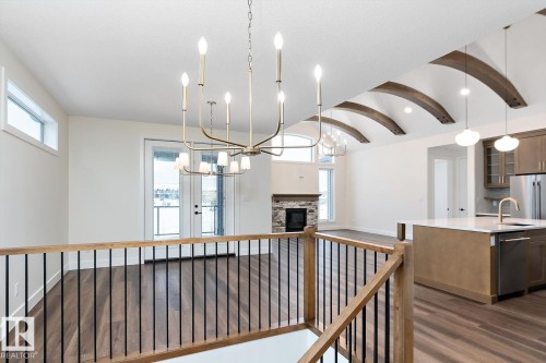 Hallway featuring a barrel ceiling, dark wood-type flooring, a chandelier, and an upstairs landing - 128 Lilac Close, Leduc, AB 