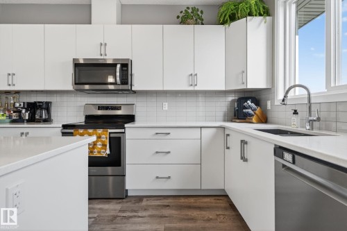 Kitchen with stainless steel appliances, white cabinetry, and light stone countertops - 211 Sturtz Bend, Leduc, AB - Indoor Photo Showing Kitchen With Stainless Steel Kitchen With Upgraded Kitchen