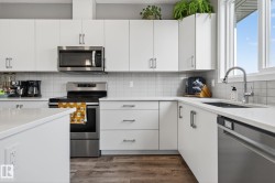 Kitchen with stainless steel appliances, white cabinetry, and light stone countertops - 