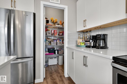 Kitchen featuring freestanding refrigerator, white cabinetry, and dark wood finished floors - 211 Sturtz Bend, Leduc, AB - Indoor Photo Showing Kitchen