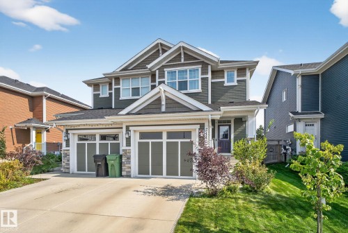 Craftsman-style house featuring driveway, stone siding, a garage, and a front yard - 211 Sturtz Bend, Leduc, AB - Outdoor With Facade