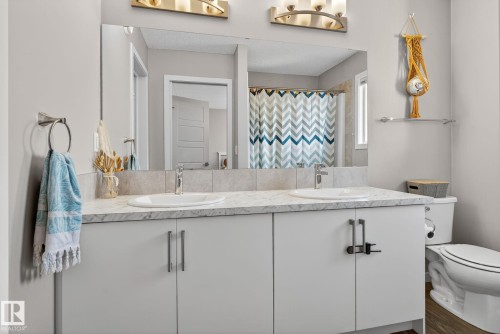 Full bath with double vanity, curtained shower, and dark wood-style floors - 211 Sturtz Bend, Leduc, AB - Indoor Photo Showing Bathroom