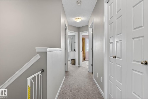 Hall with an upstairs landing, light colored carpet, and a textured ceiling - 211 Sturtz Bend, Leduc, AB - Indoor Photo Showing Other Room