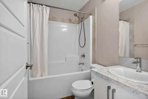 Full bath featuring a textured ceiling, vanity, and shower / tub combo with curtain - 211 Sturtz Bend, Leduc, AB - Indoor Photo Showing Bathroom