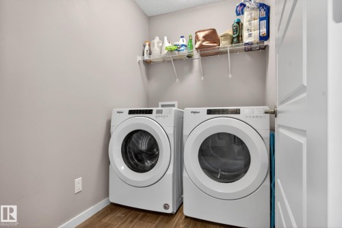 Laundry area featuring wood finished floors, independent washer and dryer, and a textured ceiling - 211 Sturtz Bend, Leduc, AB - Indoor Photo Showing Laundry Room