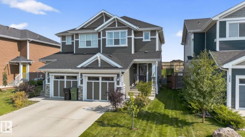 Craftsman-style home with concrete driveway, roof with shingles, an attached garage, a front yard, and stone siding - 211 Sturtz Bend, Leduc, AB - Outdoor With Facade