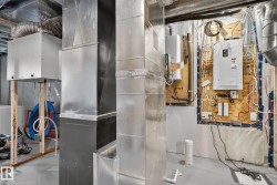 Utility room featuring heating unit, tankless water heater, and electric panel - 