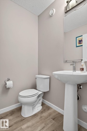 Half bath featuring light wood-style floors and a textured ceiling - 211 Sturtz Bend, Leduc, AB - Indoor Photo Showing Bathroom