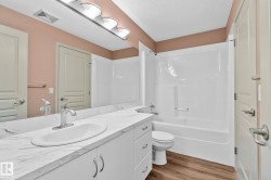 Bathroom featuring vanity, light wood-style flooring, a textured ceiling, and bathtub / shower combination - 