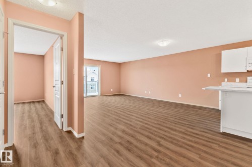 Unfurnished living room with dark wood-style flooring and a textured ceiling - 406 16035 132 Street Nw, Edmonton, AB - Indoor Photo Showing Other Room