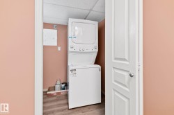 Laundry area featuring a drop ceiling, wood finished floors, electric panel, and stacked washer / dryer - 